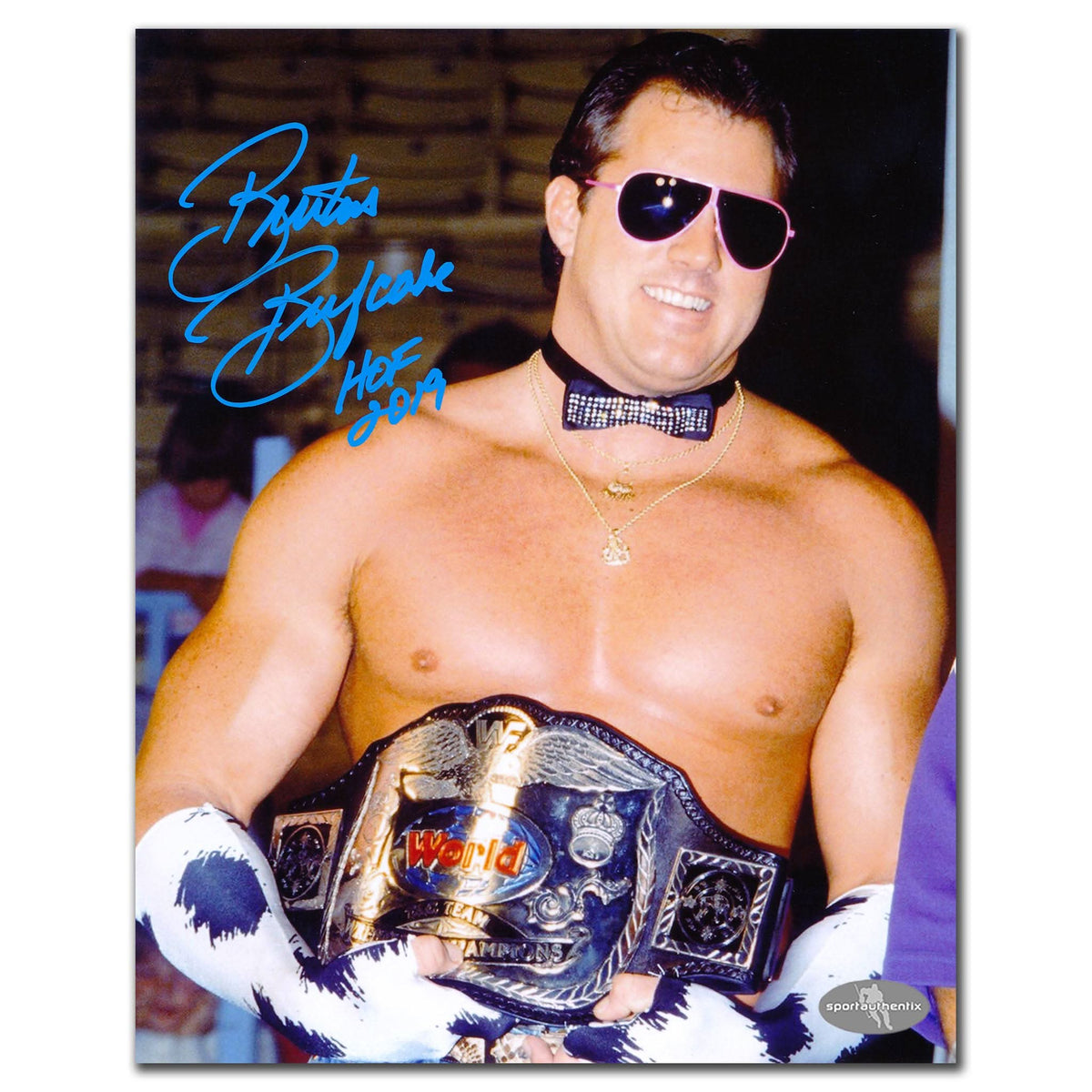 A smiling wrestler in sunglasses poses with a signed 8x10 photo, Brutus The Barber Beefcake WWE Intercontinental Champion.