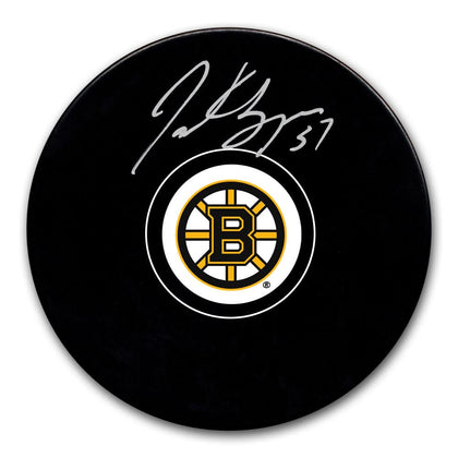 Patrice Bergeron Boston Bruins signed hockey puck, showcasing the Bruins logo and Bergerons silver autograph above the emblem.