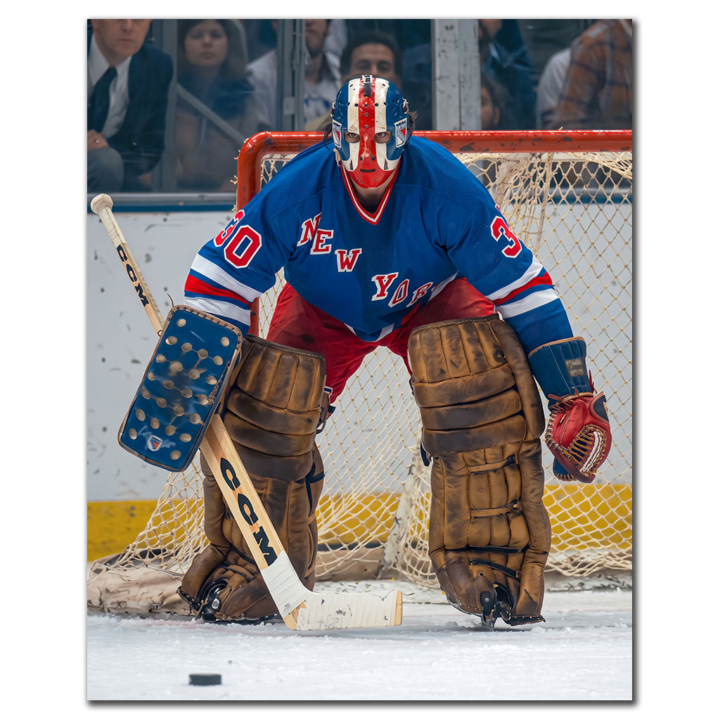 John Davidson New York Rangers 8x10 hockey photo wearing a blue jersey and red, white and blue goalie mask while crouched in front of the net with the puck on the ice for autograph pre-order