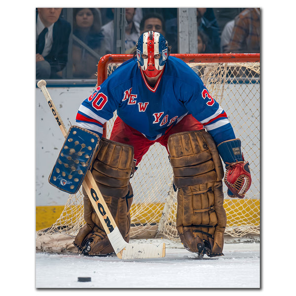 John Davidson New York Rangers 8x10 hockey photo wearing a blue jersey and red, white and blue goalie mask while crouched in front of the net with the puck on the ice for autograph pre-order