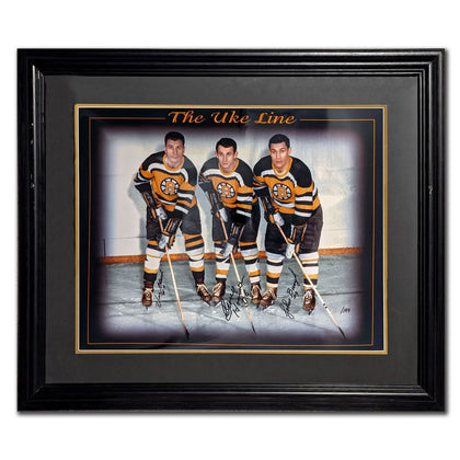 Framed 23x27 Bruins memorabilia featuring an autographed UKE LINE photo of Vic Stasiuk, Bronco Horvath, and Johnny Bucyk with sticks.