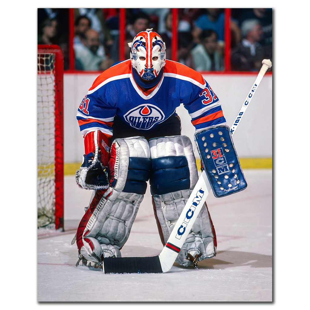 Grant Fuhr in a ready stance wearing a blue Edmonton Oilers uniform and goalie mask