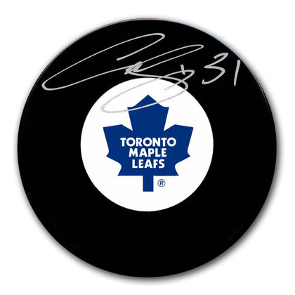 Curtis Joseph signed puck for the Toronto Maple Leafs, showcasing the teams blue maple leaf logo and a white autograph on its surface.