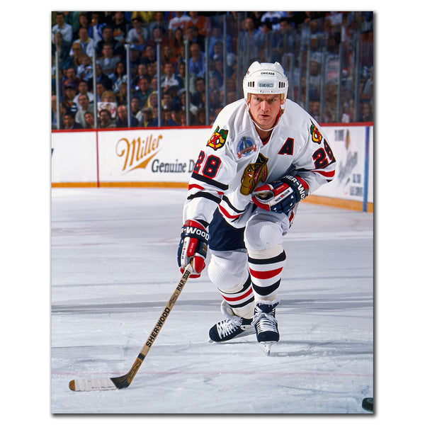 Steve Larmer carrying the puck in a white Chicago Blackhawks uniform