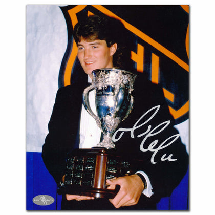 A young man in a suit holds a framed, autographed 8x10 photo titled Mario Lemieux Pittsburgh Penguins 1985 Calder by an NHL logo.
