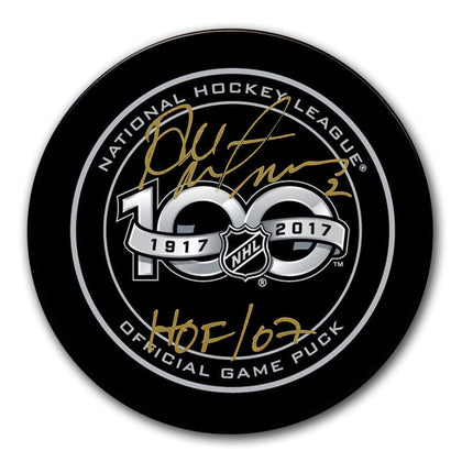 Autographed Al MacInnis NHL TOP 100 official game puck with HOF 02 inscription, COA included.