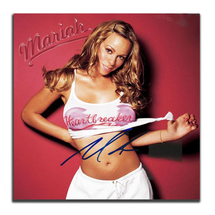 Woman in a white crop top by a red backdrop holds an autographed Mariah Carey HEARTBREAKER pink vinyl LP record.