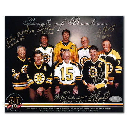 Six men in Bruins gear pose with a signed, inscribed 8x10 photo labeled “Boston Bruins 80th Season BEST OF BOSTON Autographed.”.