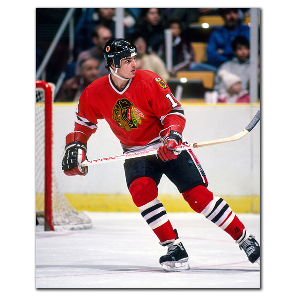 Ed Olczyk holding his stick while skating in a red Chicago Blackhawks jersey