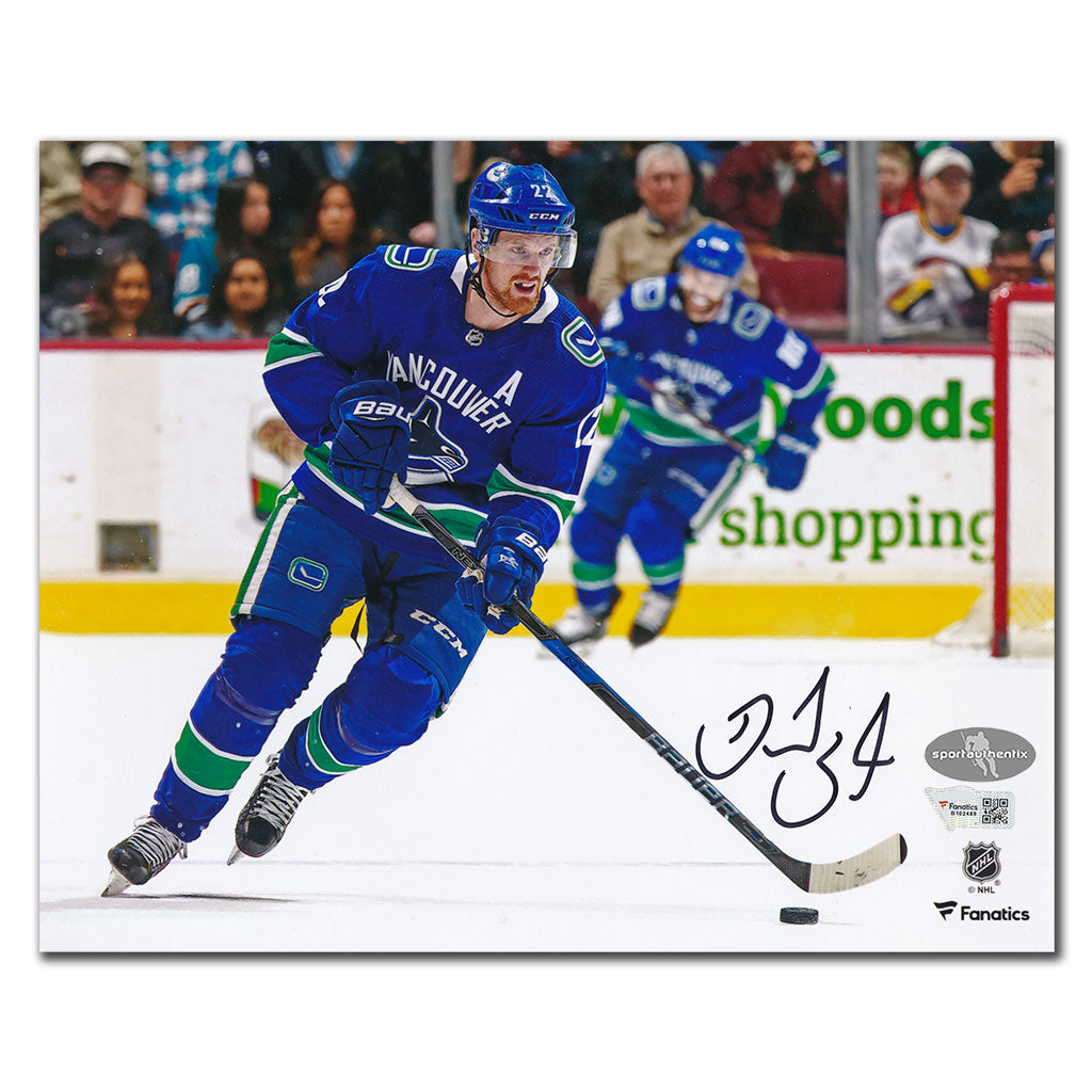 Daniel Sedin autographed Vancouver Canucks 8x10 photo skating in blue jersey with puck