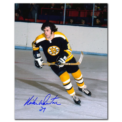 A Boston Bruins player skates on the ice, prominently displaying a signed 8x10 Mike Walton autographed photo in hand.