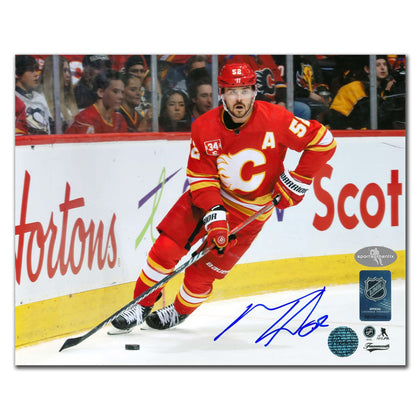 MacKenzie Weegar skates as fans watch, featured on an autographed 8x10 Calgary Flames photo—perfect memorabilia for collectors.